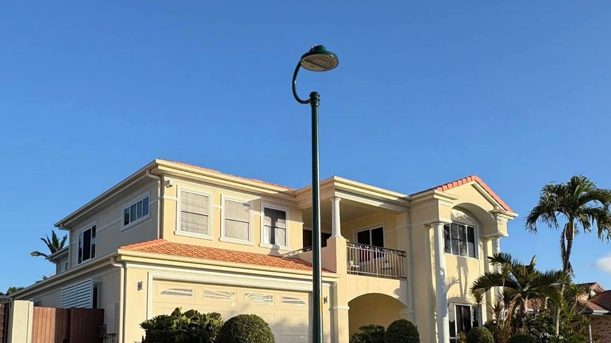 A two storey rendered home with palms in the front garden