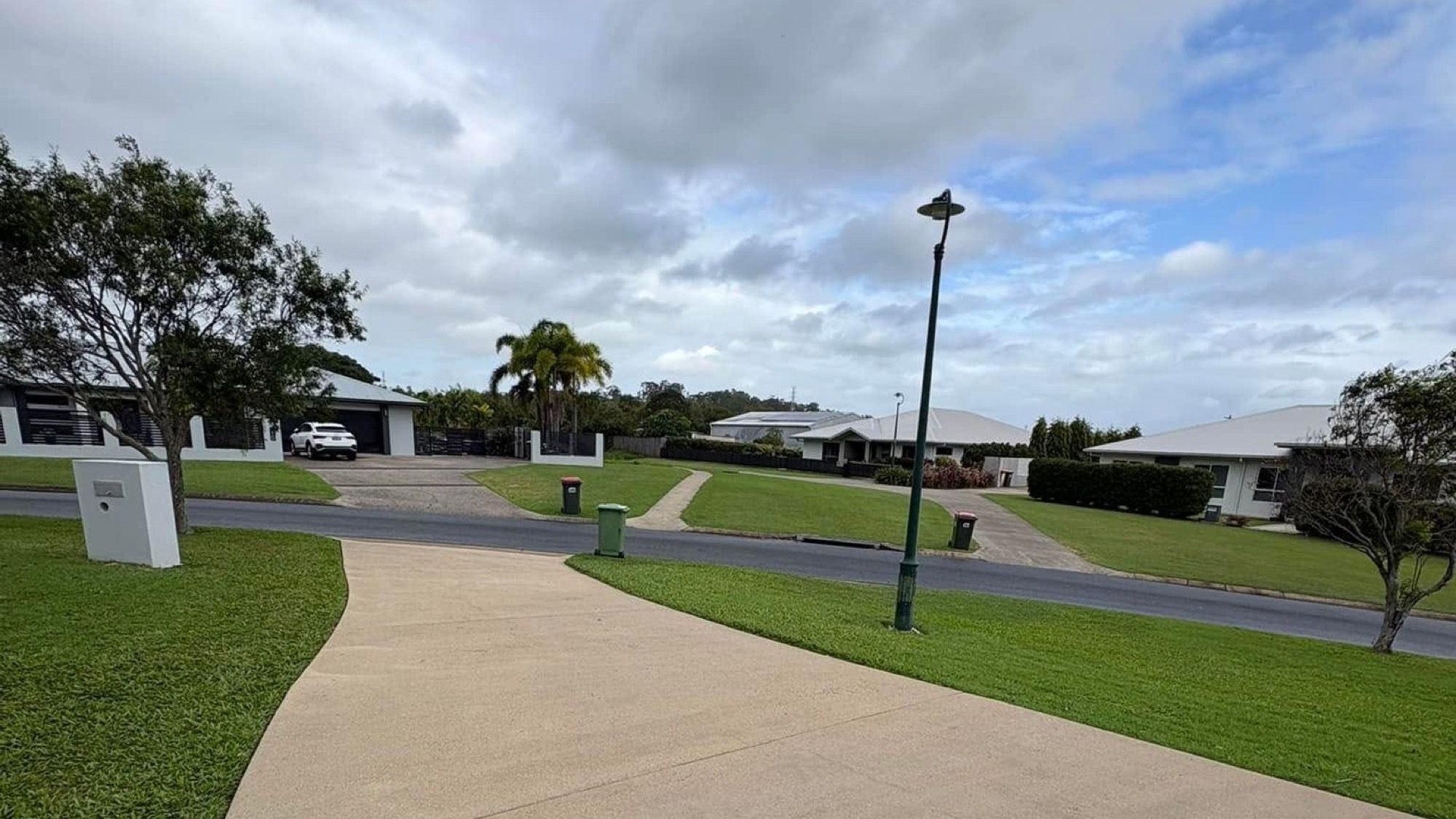 A wide concrete footpath running past Mackay homes and palms