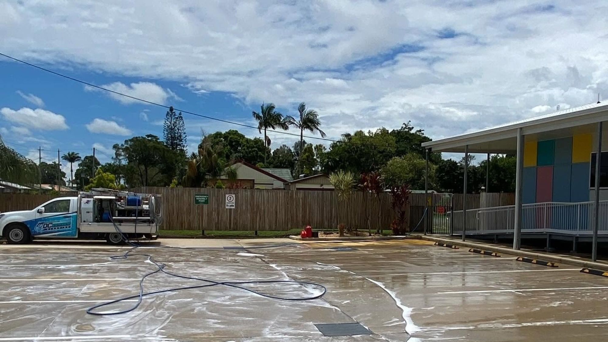 A commercial carpark being washed down beside a painted building