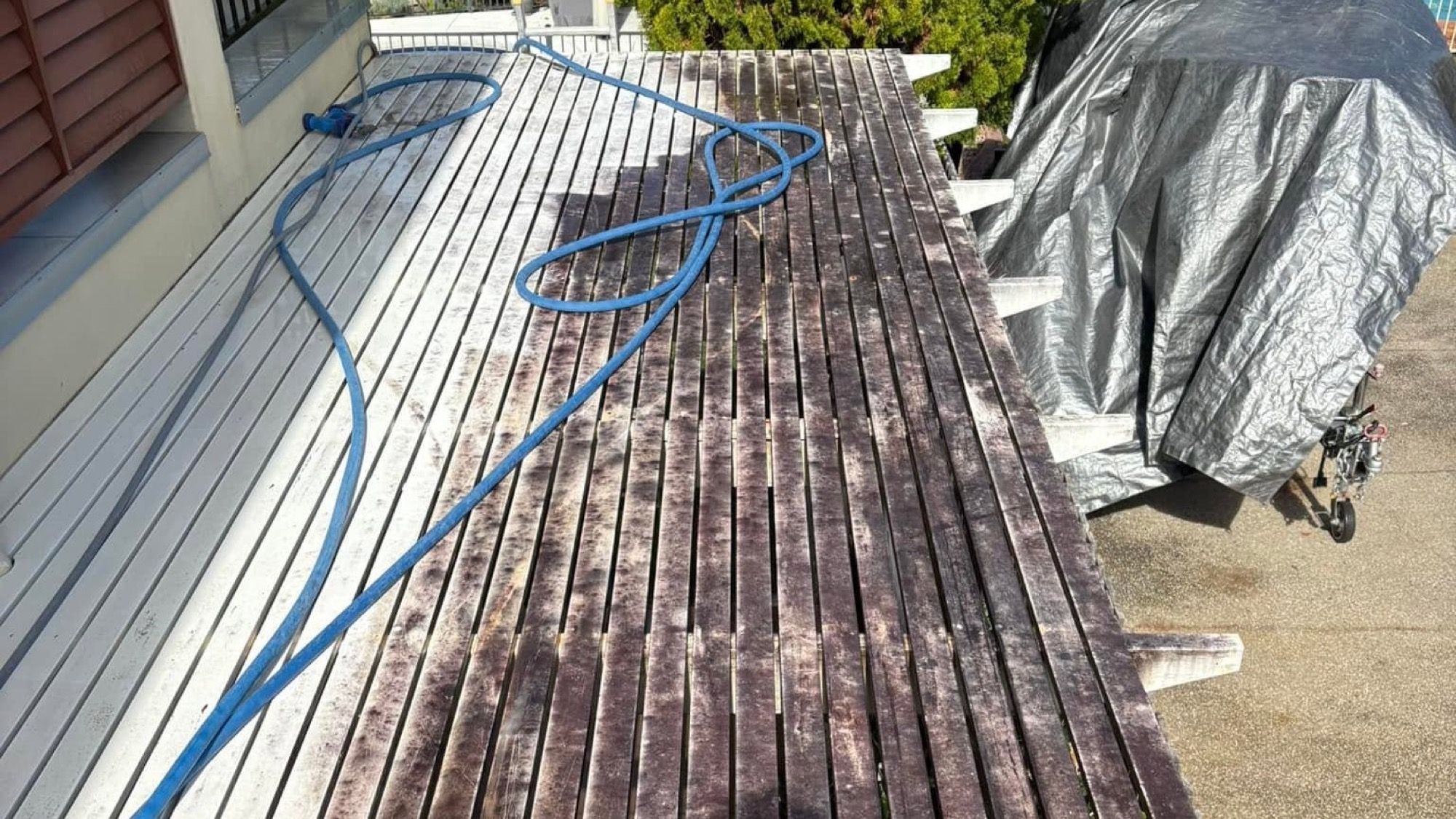 A timber deck being washed with water running across the boards