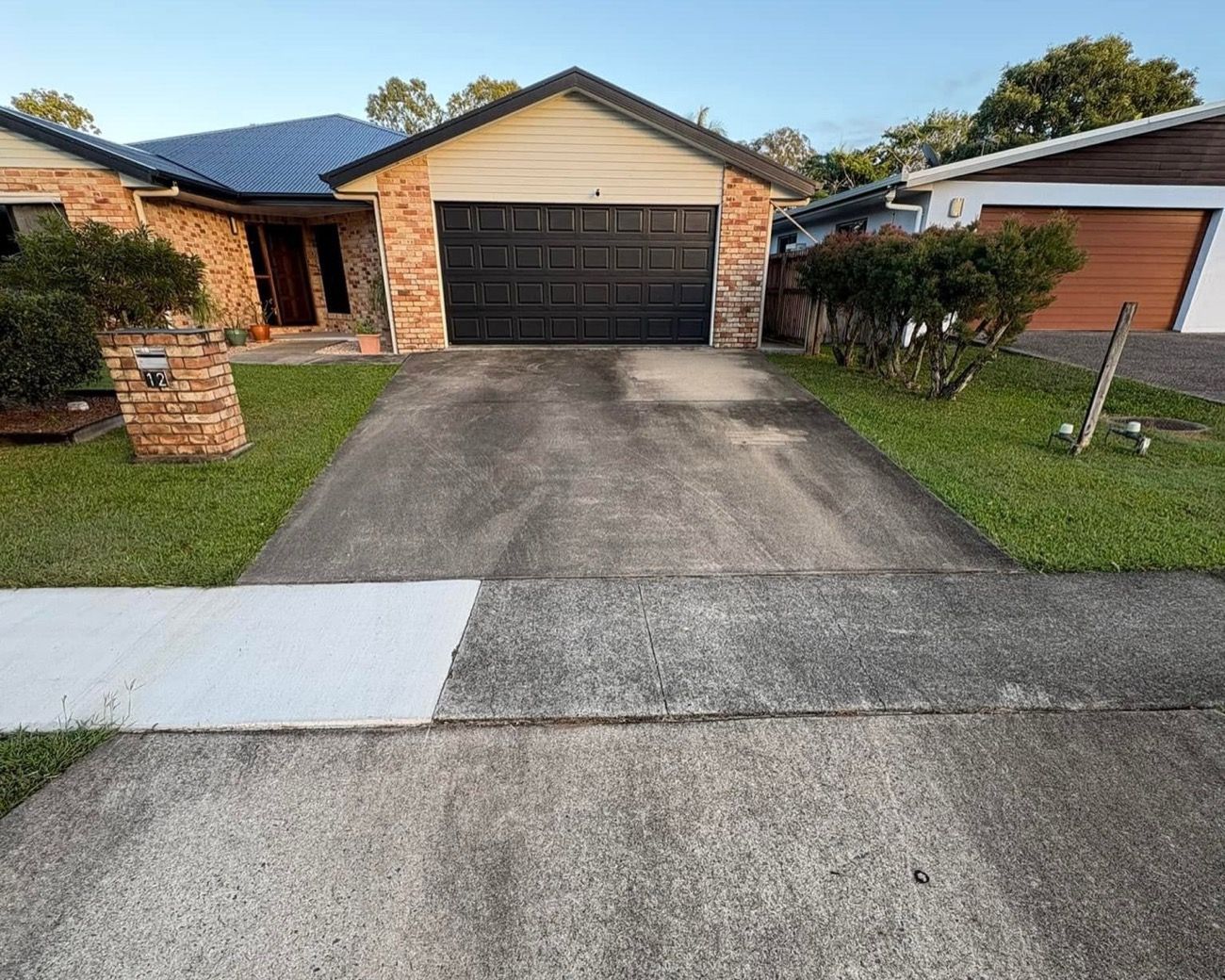A concrete driveway with a clear line between the washed and unwashed sections