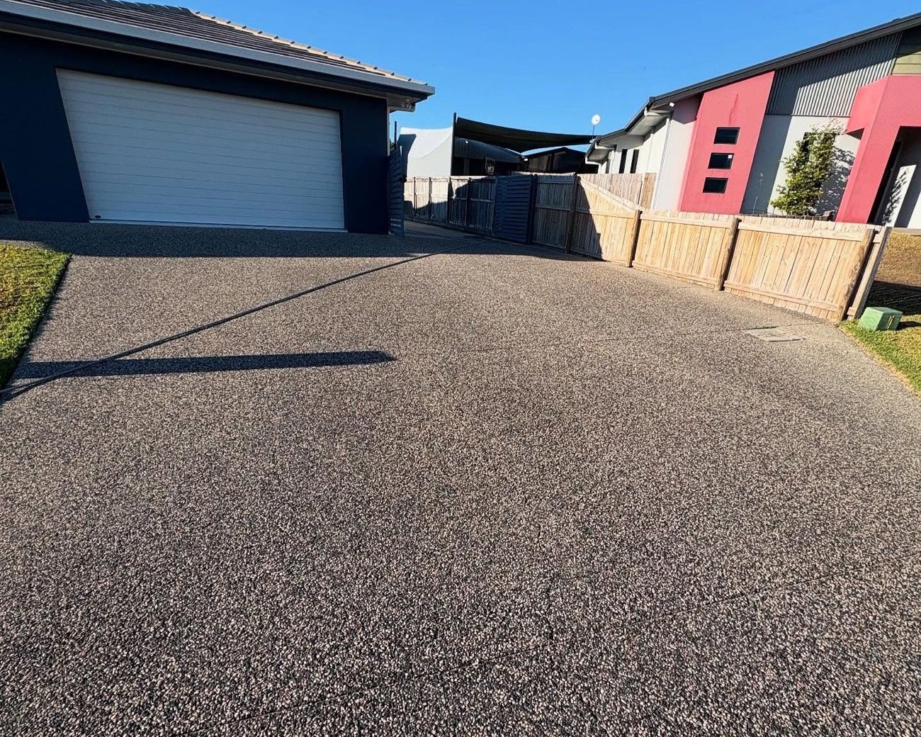An exposed aggregate driveway beside a garage