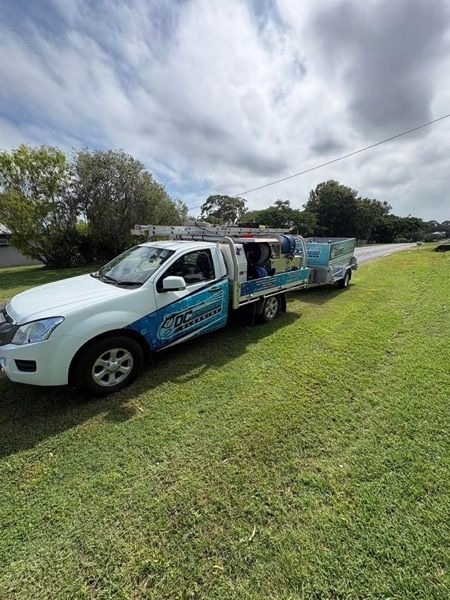 The DC Exterior Cleaning ute and trailer parked on a grass verge