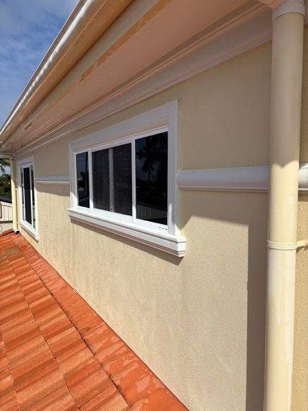 A rendered wall and the edge of a terracotta tiled roof