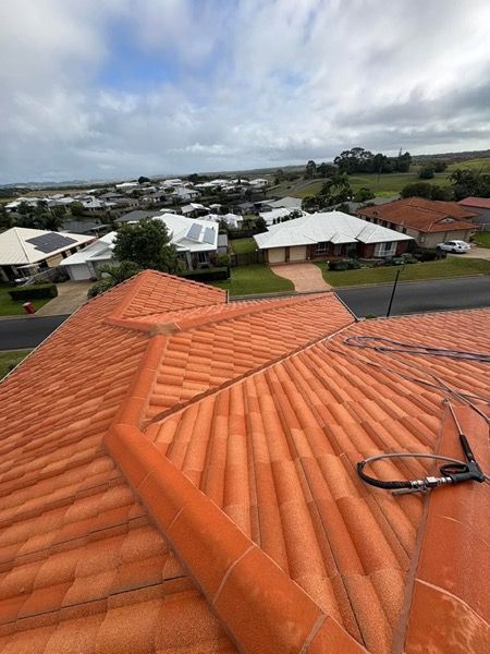 Terracotta tiled roofs across a street with a hose laid over one of them