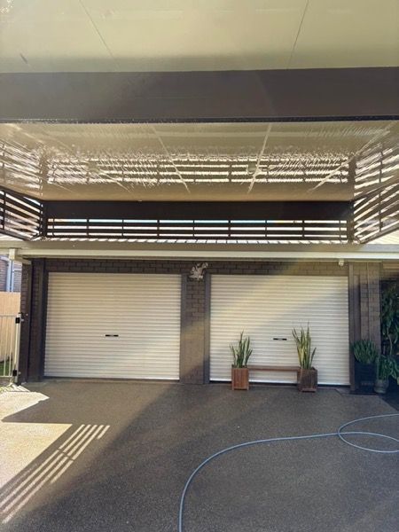 A garage and driveway with a cleaning hose laid out across the concrete
