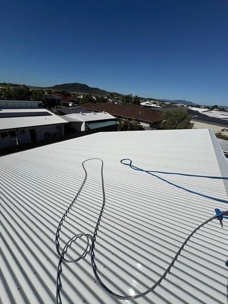 A wide metal roof with a hose across it and hills in the distance