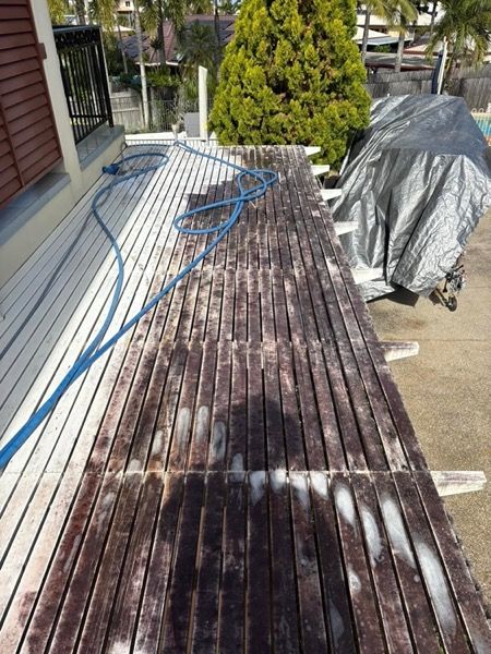 A timber deck being washed with water running across the boards