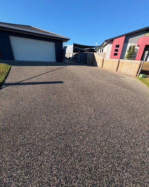 An exposed aggregate driveway beside a garage