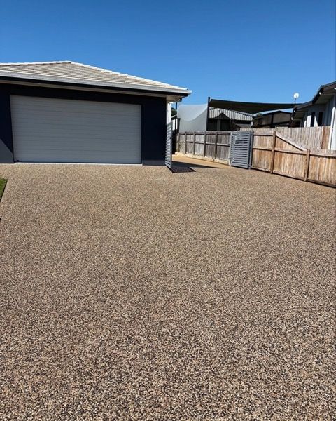 An exposed aggregate driveway running to a fence line