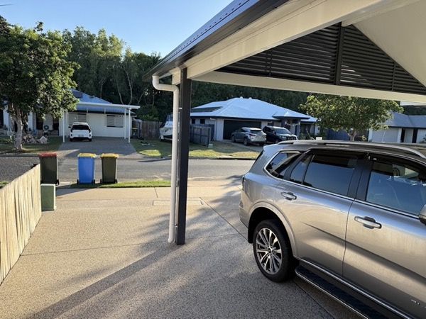 A car parked on a concrete driveway under a carport