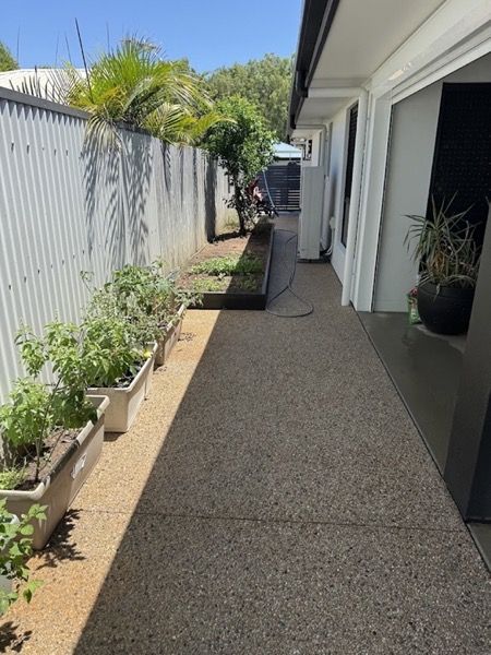 A side path beside a house with potted plants along it