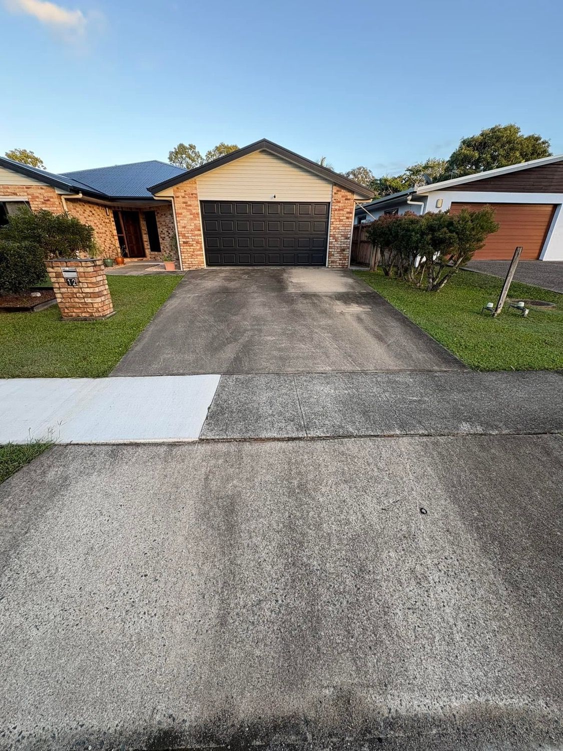 A concrete driveway with a clear line between the washed and unwashed sections